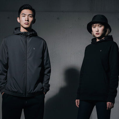 Two people standing against a dark background with shadows.